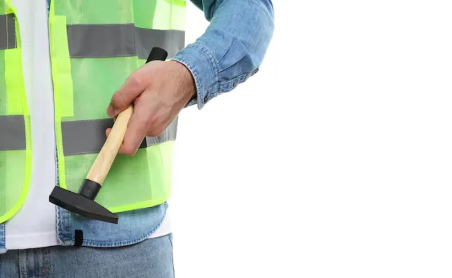 Trabajador con chaleco de seguridad y martillo